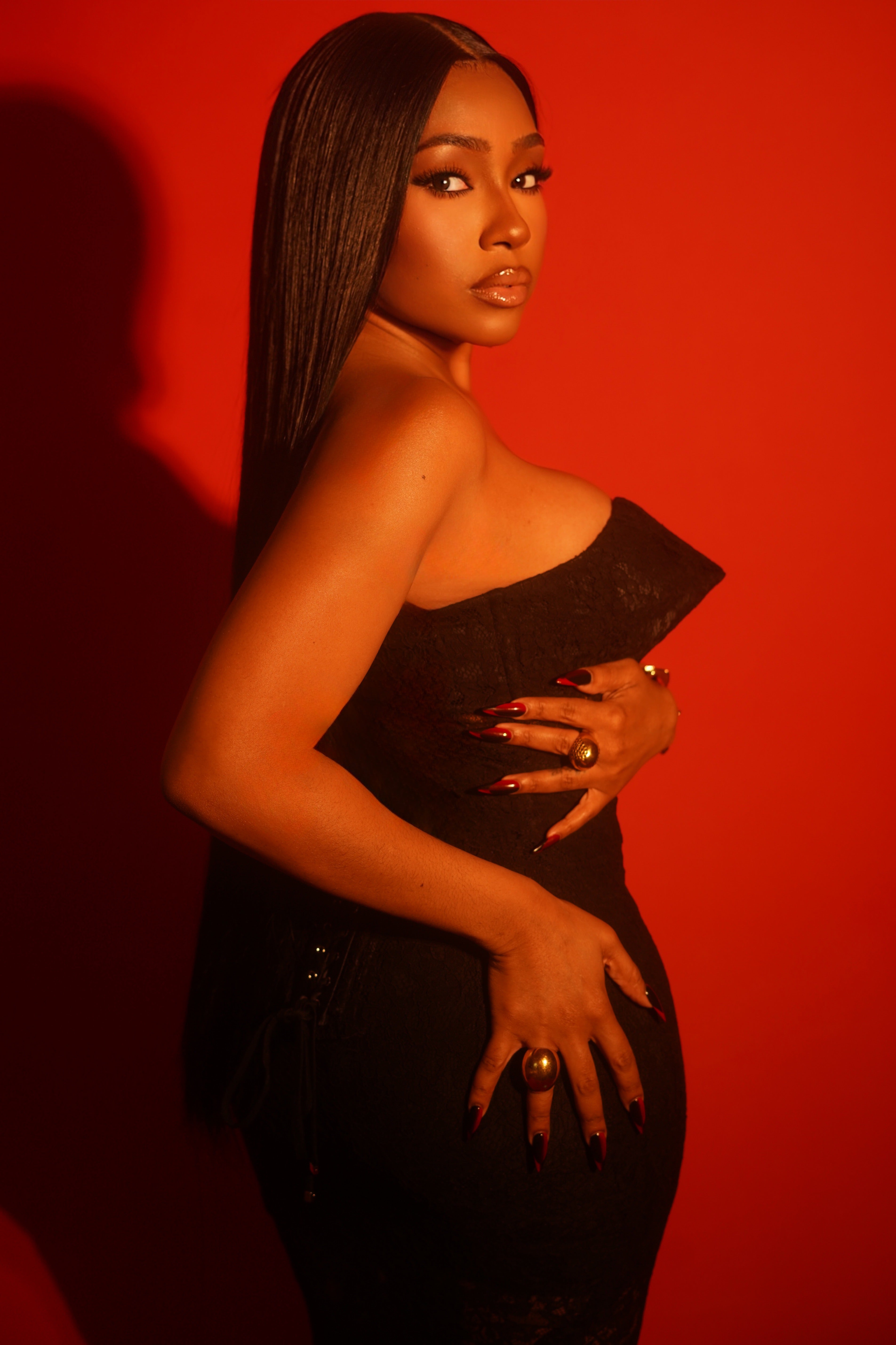 Woman in a strapless black dress against a red background